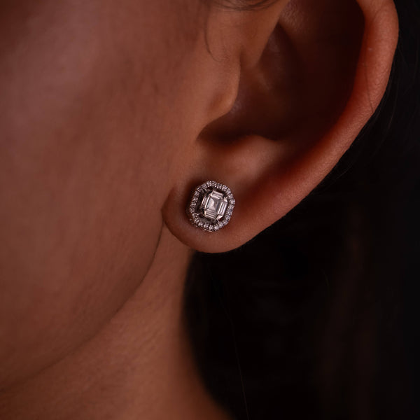 Close-up of a Minifora brand elegant stud earring featuring a radiant lab-created Asscher-cut diamond, encircled by a halo of sparkling pavé-set diamonds set in polished 14K white gold, showcased on a model's ear 