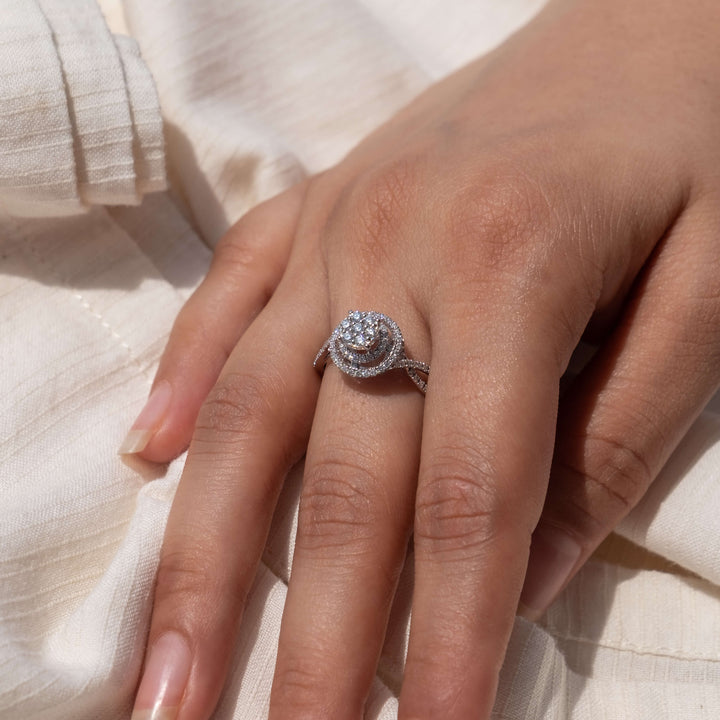 "Featuring Minifora's Celestial Swirl engagement ring, this image captures a hand delicately adorned with a distinctive ring that boasts a spiral design of lab-created diamonds set in a 14K white gold band. The swirling halo encircles a prominent central diamond.